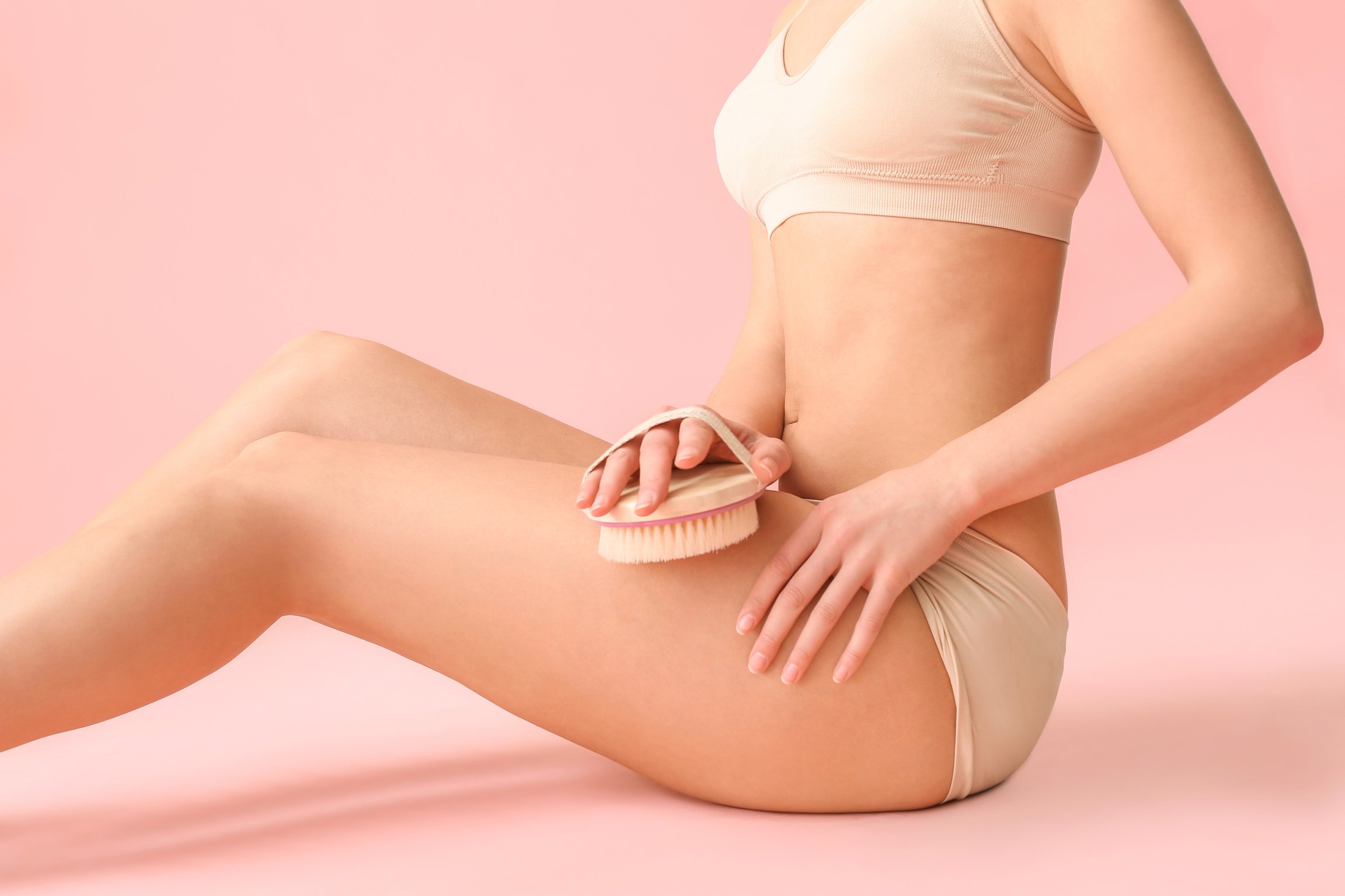 Woman with anti-Cellulite Massage Brush on Pink Background